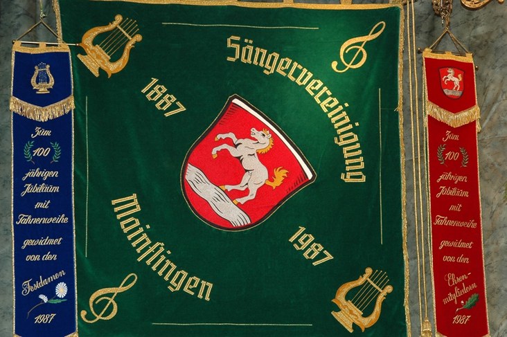 Die grüne Vereinsfahne mit dem Schimmel-Wappen und den Jahreszahlen 1887 und 1987, links und rechts bestickte Fahnenbänder zum 100-jährigen Jubiläum