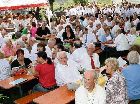 Zahlreiche Gäste und Sänger in weißen Hemden an dicht besetzten Festbänken unter dem Zeltdach am Mainufer