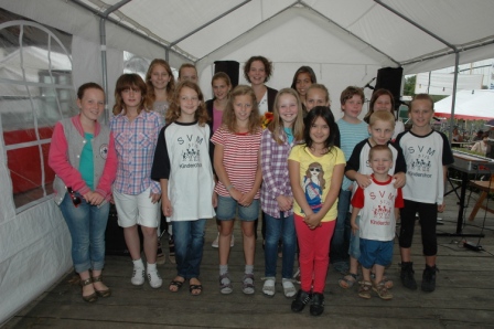 Der SVM-Kinderchor mit seiner Leiterin im Festzelt, einige Kinder in T-Shirts mit der Aufschrift „SVM Kinderchor“