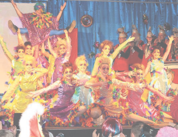 Showtanzgruppe in bunt schillernden, federbesetzten Kostümen auf der Bürgerhausbühne, im Hintergrund der Elferrat