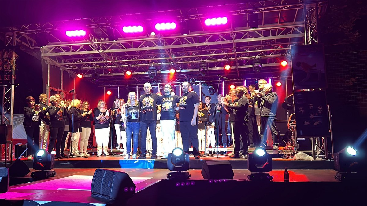 Chor und Solisten auf der Open-Air-Bühne beim Queen-Tribute-Konzert „A Kind of Magic“, umrahmt von farbigem Bühnenlicht